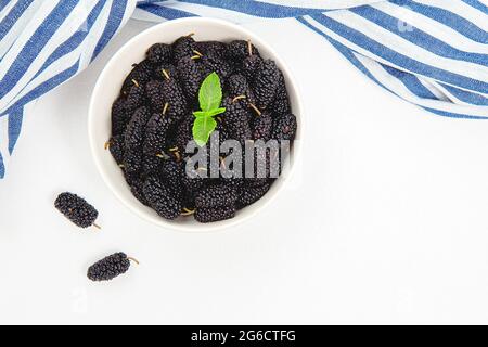 Weiße Schale voller reifer schwarzer Maulbeeren. Sommer frische Maulbeerfrüchte. Gesunde Beeren mit Vitamin C und Antioxidantien. Frische Maulbeerschüssel. Maulbeere Stockfoto