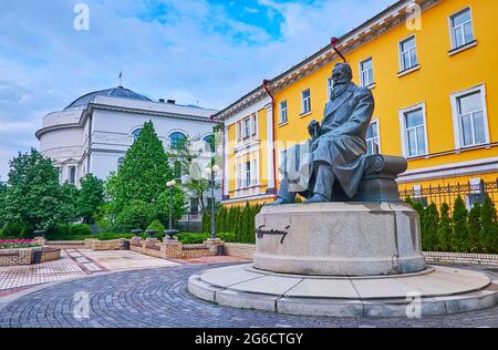 KIEW, UKRAINE - 18. MAI 2021: Das Denkmal für Mychailo Hrushevsky, angrenzend an das Gebäude der Taras Schewtschenko Universität und das Lehrerhaus (f Stockfoto