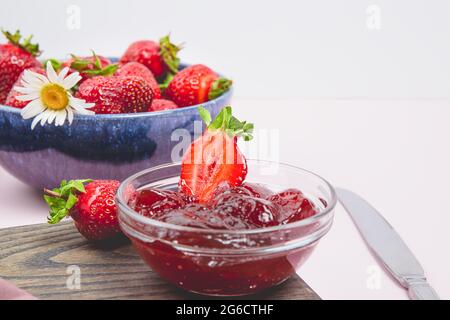 Hausgemachte Erdbeermarmelade oder Erdbeergelee mit frisch reifen Erdbeeren auf einem weißen Teller. Frühstück mit Brot Toast mit Erdbeermarmelade. Messer für s Stockfoto