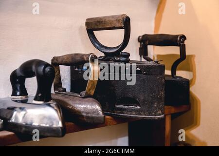 Sammlung von Vintage-Bügeleisen zum Bügeln von Kleidung. Antikes Metalleisen, ein Museumsstück antiker Haushaltsgeräte. Kabelloses Metall-Kohlemeisen Stockfoto