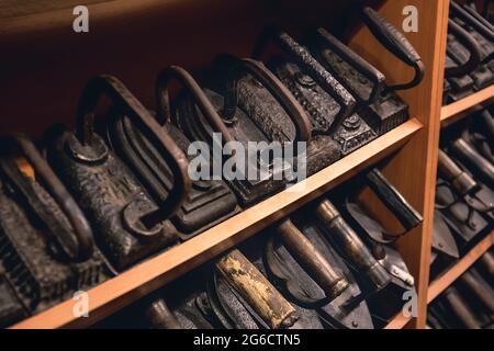 Sammlung von Vintage-Bügeleisen zum Bügeln von Kleidung. Antikes Metalleisen, ein Museumsstück antiker Haushaltsgeräte. Kabelloses Metall-Kohlemeisen Stockfoto