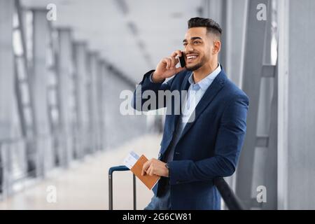 Ein Gutaussehender Geschäftsmann Aus Dem Nahen Osten, Der In Der Airport Lounge Auf Dem Handy Telefoniert Stockfoto