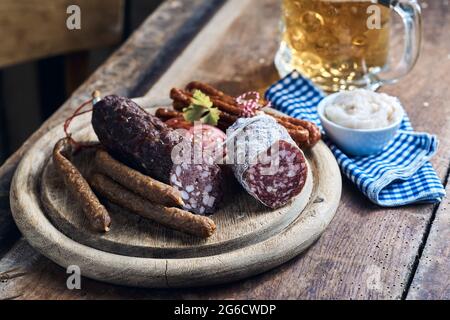 Ein großer Winkel appetitlich geräucherter Wildwurst, serviert auf Holzbrett mit einem Pint Bier Stockfoto