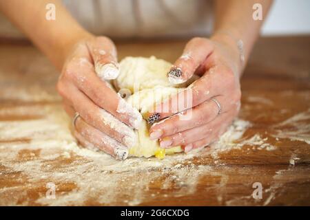 Unverkennbare Hausfrau, die beim Kochen Eier über rohem Teig zerbricht Tisch in der Küche Stockfoto