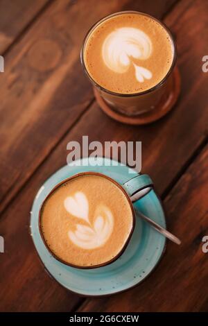 Von oben aus Keramik Tassen auf Untertassen mit frisch gebrühten Latte mit Herzen auf Schaum Stockfoto