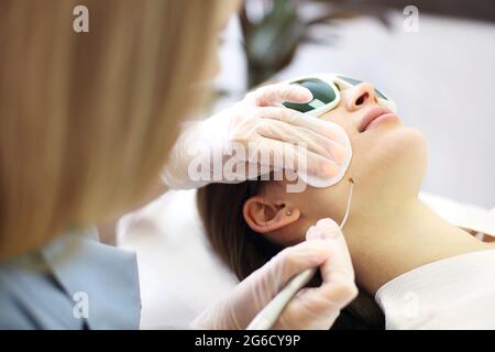 Laserentfernung von Maulwurf am Hals einer Frau in einem Schönheitssalon. Nahaufnahme Stockfoto