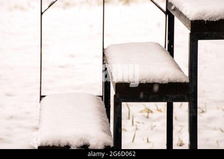 Da der Schnee immer noch fällt, sind die Stufen an einem kalten Wintertag in Missouri bereits mit dem hübschen weißen Zeug übereinander gelegt. Bokeh-Effekt und Schneebewegung. Stockfoto