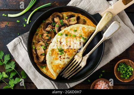 Frisches Rührei, Omelett oder Frittata mit Pilzen, Zwiebeln und frischen Kräutern auf gusseiserner Pfanne. Draufsicht mit Kopierbereich. Stockfoto