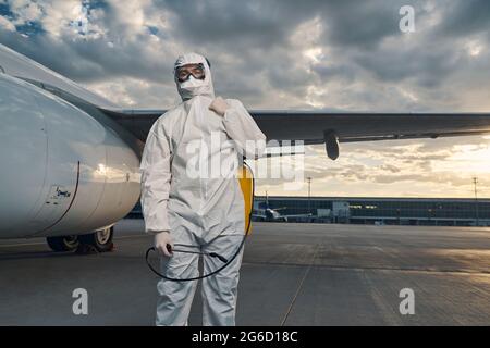 Mann in einem Hazmat-Anzug, der am Flugplatz steht Stockfoto