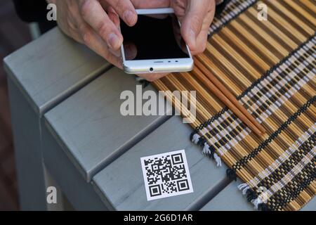 Von oben der Ernte unkenntlich männlich mit Smartphone und Scannen QR-Code des Menüs des Restaurants Stockfoto