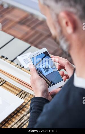 Von oben der Ernte unkenntlich männlich mit Smartphone und Scannen QR-Code des Menüs des Restaurants Stockfoto