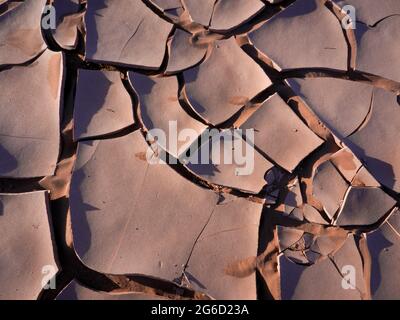 Ausgetrockneter Sand bildet eine rissige Tonschicht. Stockfoto