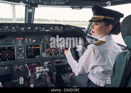 Nachdenkliche, dunkelhaarige Co-Pilotin sitzt im Cockpit Stockfoto