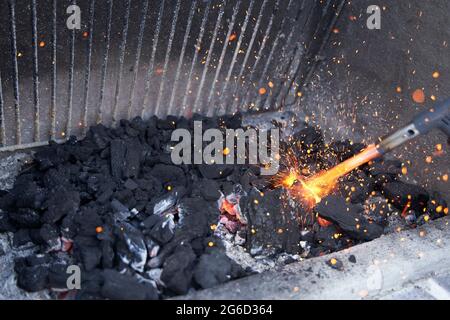 Bokeh von rotem Feuer von einem Gasbrenner, glühende Kohlen und Funken auf einem Grillhintergrund Stockfoto