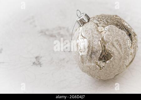 Silberne Weihnachtskugel mit Struktur auf weiß gemustertem Hintergrund und Platz zum Kopieren Stockfoto