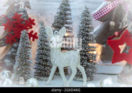 Glitzerndes Hirsch vor verschiedenen Tannen als Weihnachtsdekoration Stockfoto