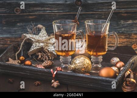 Zwei Gläser mit Tee auf einem weihnachtlich geschmückten Holztablett Stockfoto