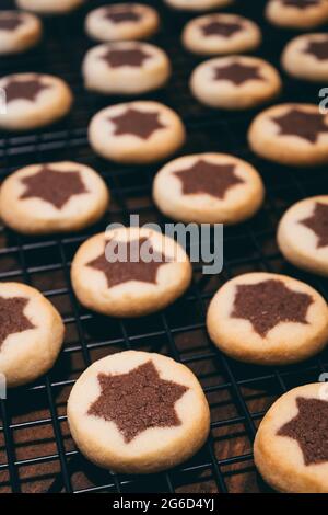 Schwarzes Kühlregal mit hausgemachten runden weihnachtsplätzchen mit einem Kakaostern in der Mitte, selektiver Fokus Stockfoto