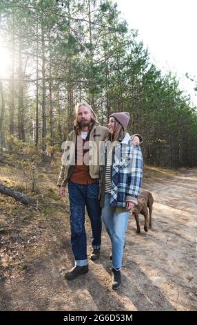 Junges Paar, das sich umarmt und während ihres Spaziergangs im Wald miteinander spricht Stockfoto