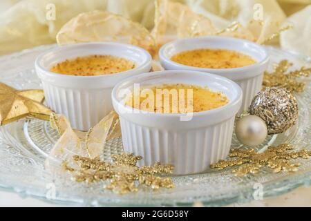 Creme Brulee: Traditionelles dessert mit französischer Vanillecreme und karamellisiertem Zucker. Drei Portionen serviert auf einem verzierten Glasplatte mit einem goldenen Stockfoto