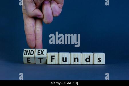 Indexfonds vs. ETF-Symbol. Geschäftsmann dreht einen Würfel und ändert die Wörter „ETF, Exchange-Traded Fund“ in „Indexfonds“. Schöner grauer Hintergrund, kopieren Spa Stockfoto