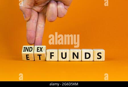 Indexfonds vs. ETF-Symbol. Geschäftsmann dreht einen Würfel und ändert die Wörter „ETF, Exchange-Traded Fund“ in „Indexfonds“. Schöner orangefarbener Hintergrund, Kopie s Stockfoto