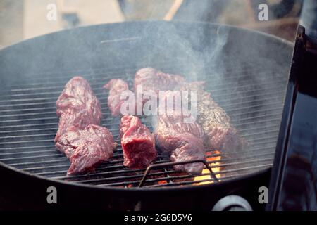 Nahaufnahme von Fleischstücken, die auf dem Grillrost liegen, und Braten zum Abendessen Stockfoto