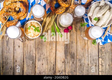 Oktoberfest-Food-Hintergrund, traditionelle bayerische Festtagsmenüs, Würstchen mit Brezeln, Sauerkraut, Bierglas und Tassen auf sonnenbeleuchtetem Holzbac Stockfoto