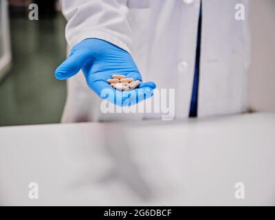 Crop anonyme Wissenschaftler in Schutzhandschuhen stehen mit Haufen von Kapseln im Labor Stockfoto