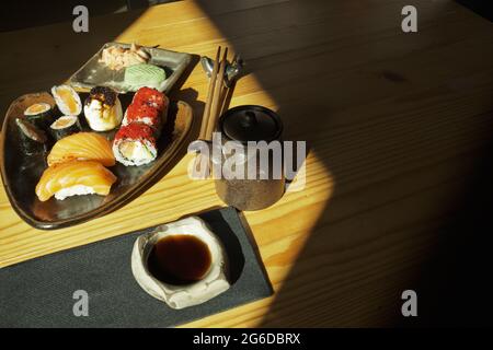 Von oben Teller mit verschiedenen Sushi-Brötchen, serviert auf dem Tisch mit Essstäbchen und Sojasauce im japanischen Restaurant Stockfoto