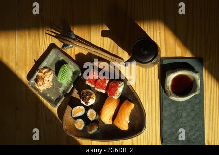 Von oben Teller mit verschiedenen Sushi-Brötchen, serviert auf dem Tisch mit Essstäbchen und Sojasauce im japanischen Restaurant Stockfoto