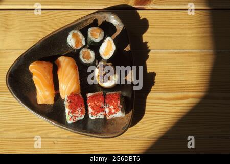 Von oben Teller mit verschiedenen Sushi-Brötchen, serviert auf einem Holztisch im japanischen Restaurant Stockfoto