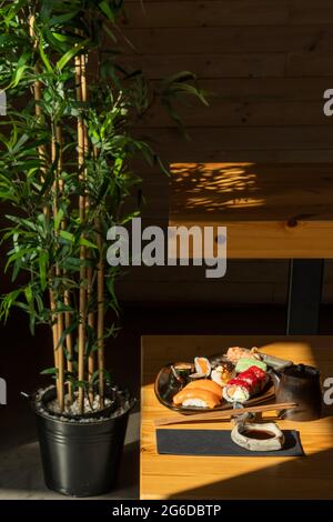 Teller mit verschiedenen Sushi-Rollen, serviert auf dem Tisch mit Essstäbchen und Sojasauce im japanischen Restaurant Stockfoto