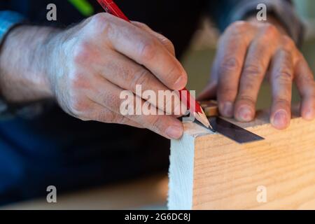 Crop professionelle Holzarbeiter mit Bleistift und Messwerkzeug Marken auf Holzbrett machen, während die Erstellung von Handwerk Objekt in der Schreinerei Werkstatt Stockfoto