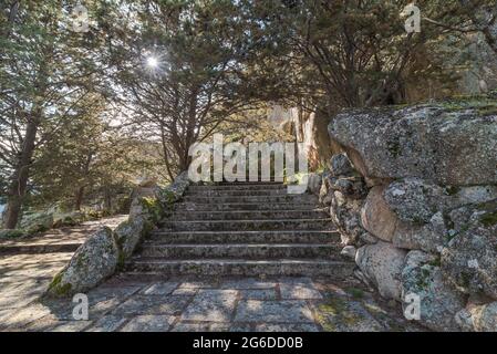 Raue Felstreppe in der Nähe von grünen Bäumen vor einem alten Gebäude am Morgen im Nationalpark Sierra de Guadarrama in Madrid, Spanien Stockfoto