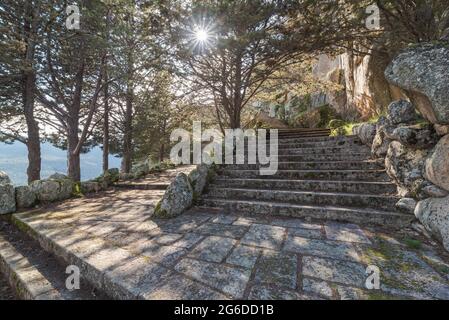 Raue Felstreppe in der Nähe von grünen Bäumen vor einem alten Gebäude am Morgen im Nationalpark Sierra de Guadarrama in Madrid, Spanien Stockfoto