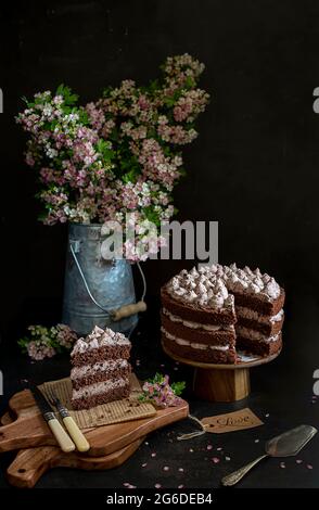 Food Fotografie von Schokoladenkuchen, Blumen, schwarzer Hintergrund, rustikal, vintage Stockfoto