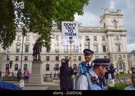 London, Großbritannien. Juli 2021. Ein Protestler folgt Polizeibeamten mit einem Schild „Rede nicht mit ihnen“. Demonstranten versammelten sich auf dem Parliament Square, um gegen das Gesetz über Polizei, Kriminalität, Verurteilung und Gerichte zu protestieren, von dem viele sagen, dass es der Polizei mehr Macht über Proteste in Großbritannien geben würde. (Kredit: Vuk Valcic / Alamy Live News) Stockfoto