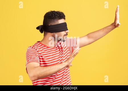 Profil Porträt bärtiger Mann mit Sehproblemen trägt schwarze Binde auf Augen, die die Hände ausstrecken, lernt durch Berührung zu navigieren, entwickelt Sinne. Stockfoto