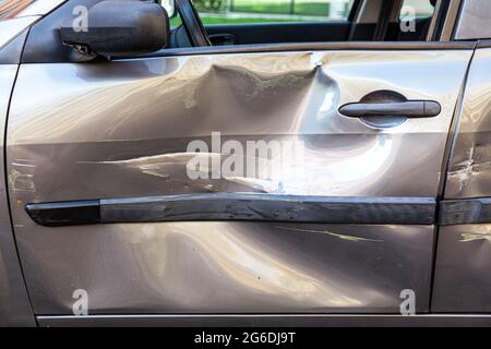 Seitenansicht des zerstörten Autos nach dem Unfall, Nahaufnahme von Beulen und Kratzern an der Autotür nach dem Verkehrsunfall, zerbrochenes Fahrzeug. Außenaufnahme. Stockfoto