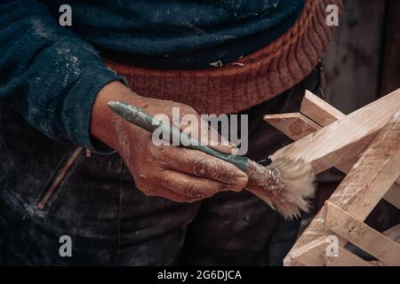 Eine Hand einer alten Frau, die auf Holz gemalt hat Stockfoto