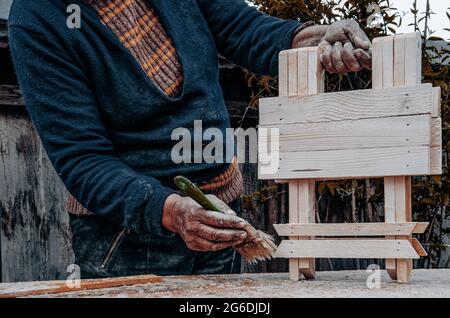 Alte Handwerker Hände malen ein Holzobjekt Stockfoto