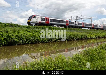 Ein Elektrozug der Klasse 720 Aventra der Greater Anglia auf der West Coast Main Line am Oxford Canal in Ansty, Warwickshire, Großbritannien Stockfoto