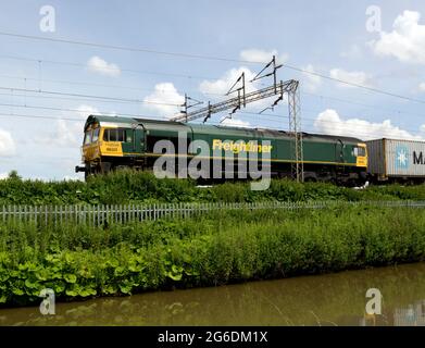 Eine Diesellokomotive der Baureihe 66, die einen freightliner-Zug auf der West Coast Main Line entlang des Oxford Canal in Ansty, Warwickshire, Großbritannien, fährt Stockfoto