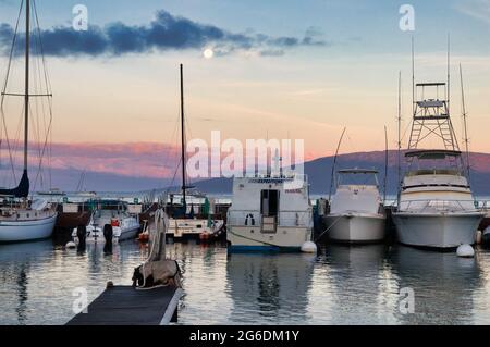 Der Hafen von Lahaina ist im Morgengrauen, der Mond geht unter und Lanai liegt in der Ferne Stockfoto