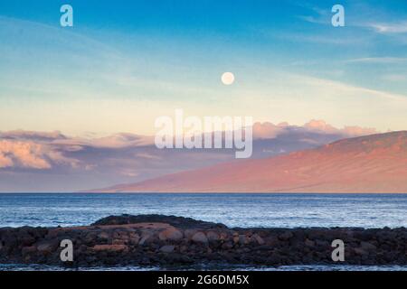 Monduntergang über dem Hafen von Lahaina bei Sonnenaufgang mit Lanai in der Ferne. Stockfoto