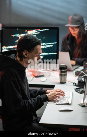 Hacker-Mann tippt im Büro vor dem Computer Stockfoto