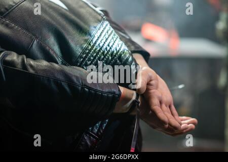 Hände in Manschetten und Rücken des gefangenen Verbrechers in schwarzer Lederjacke Stockfoto