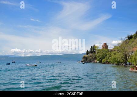 Beeindruckend schöne Aussicht vom See mit Bootsbaum, Steinen, Strand, Berg auf klaren blauen Himmel Stockfoto