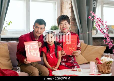 Chinesische Familie hält handgemachte rote Neujahrspostkarten Stockfoto